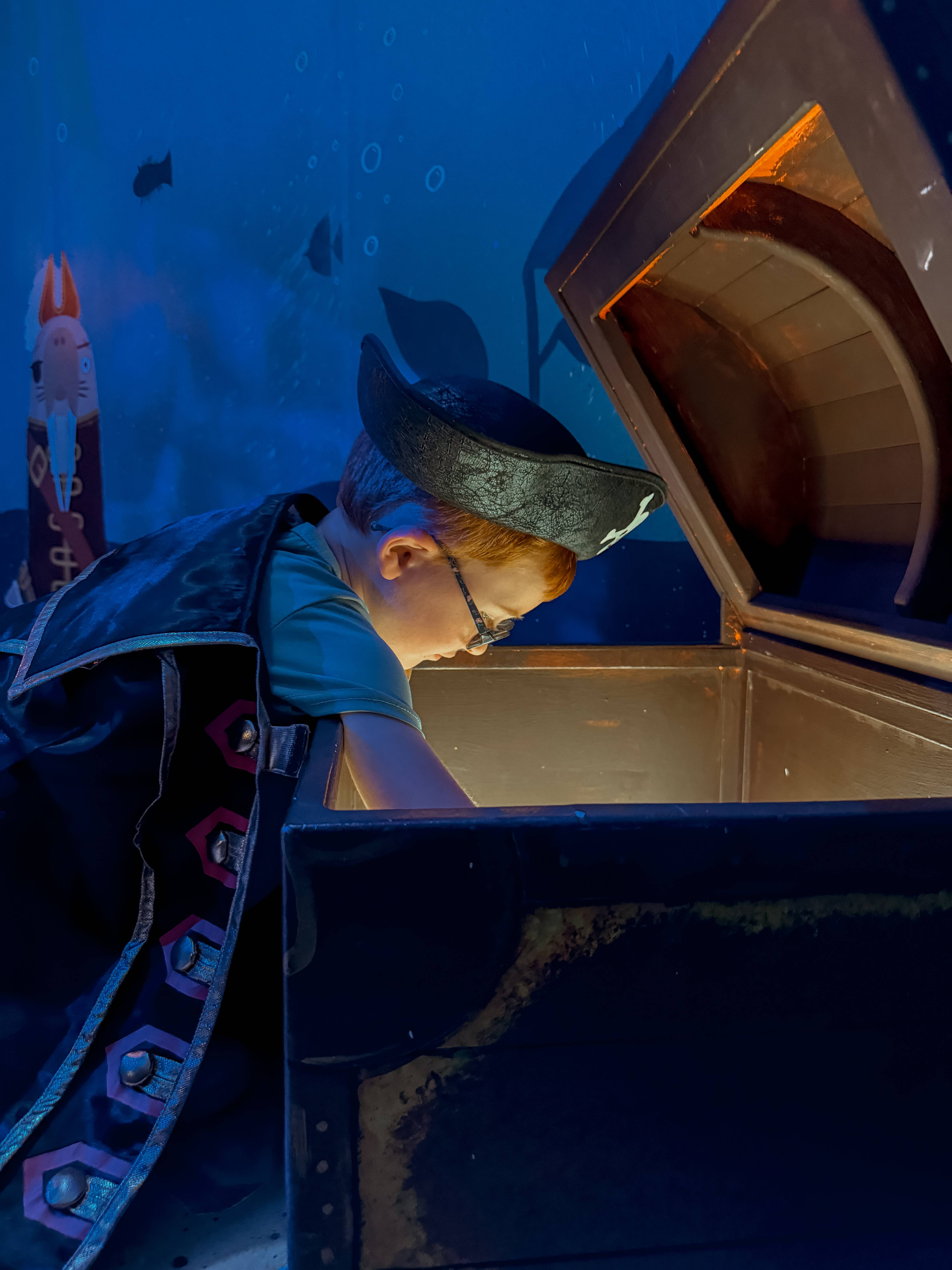 adventure photo of young boy dressed as a pirate reaching in a big glowing treature chest